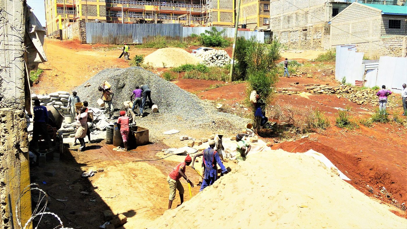 Construction workers mixing concrete with bagged cement on a site in Embu, Kenya